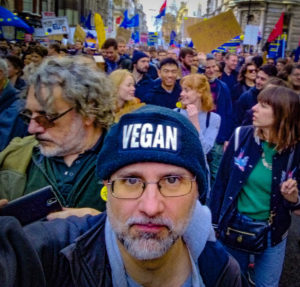 Man with a hat with the word 'Vegan' in front of a crowd