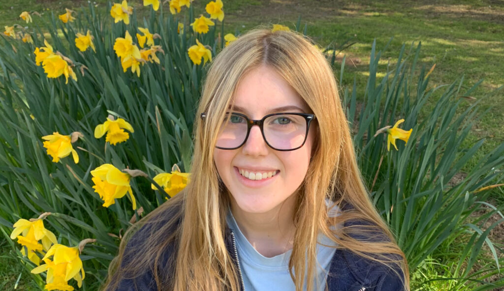 Teenager girl smiling in front of flowers