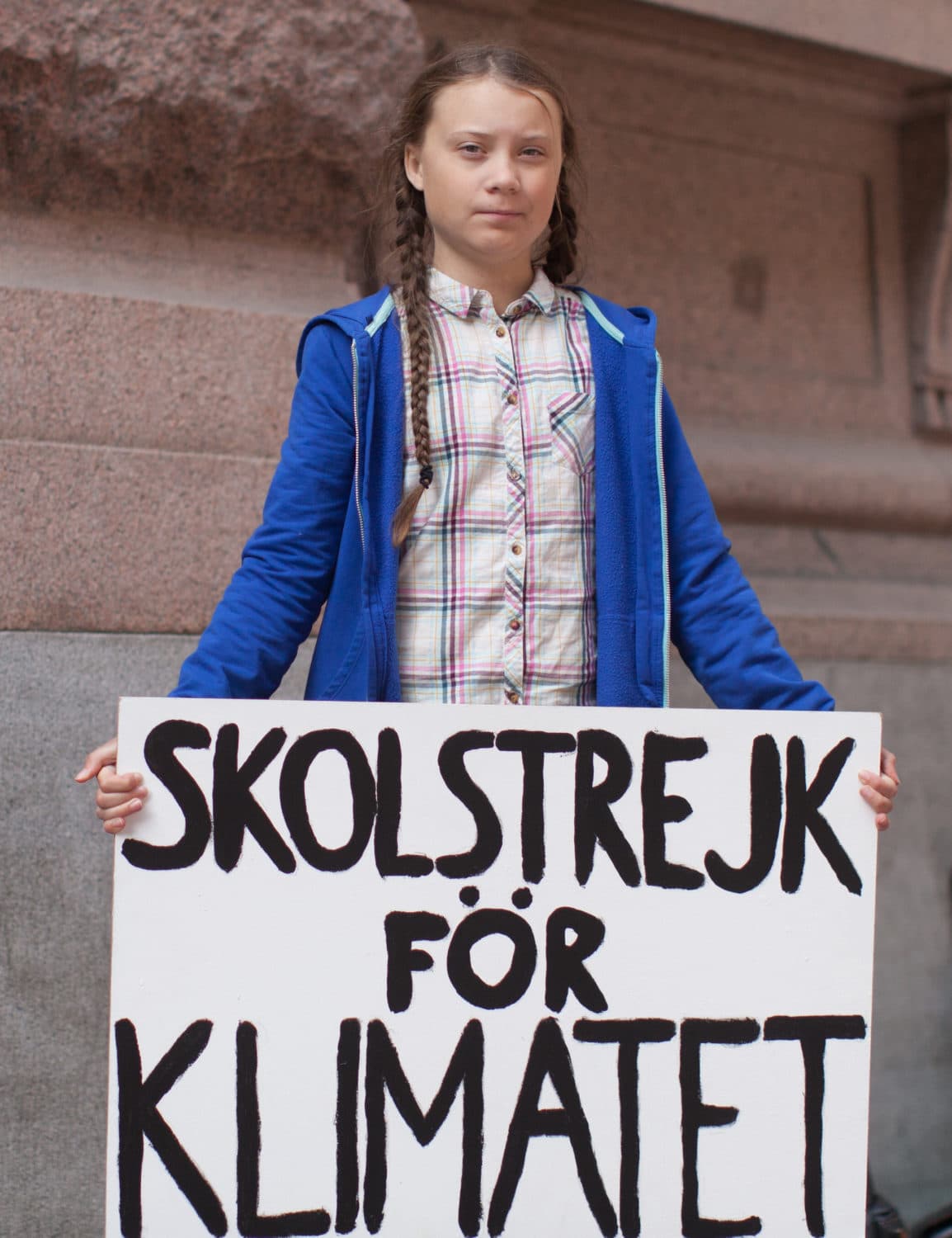 Greta Thunberg holding a sign that says in Swedish "Strike for Climate” 
