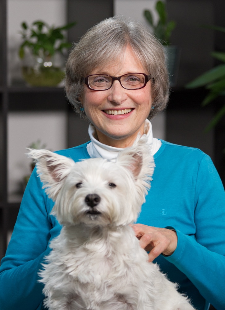 Woman with glasses holding a terrier on her lap