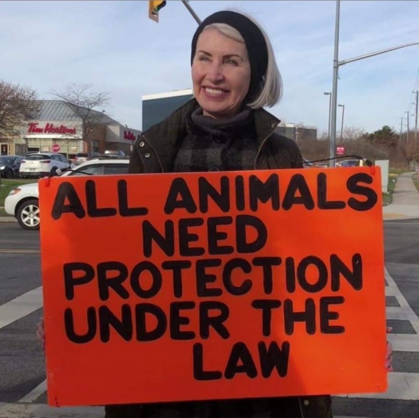 Woman with a placard that says "All Animals Need Protection under the Lasw"