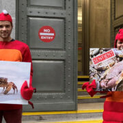 Two demonstrators dressed as crustaceans with placards in front of a UK Government building