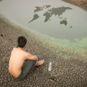 Water crisis world map, man sit on cracked earth near drying wat. By releon8211
