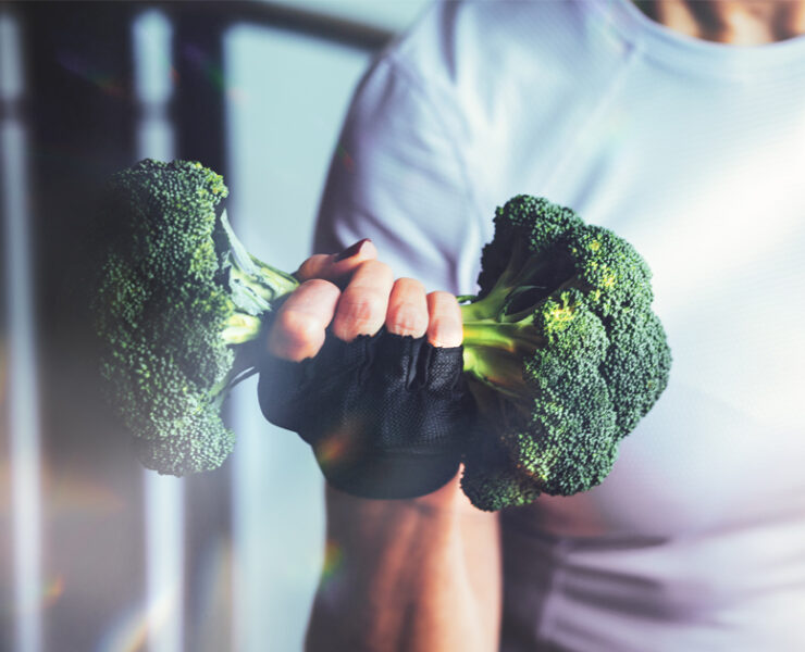 Woman in the gym lifts a broccoli in the form of a dumbbel