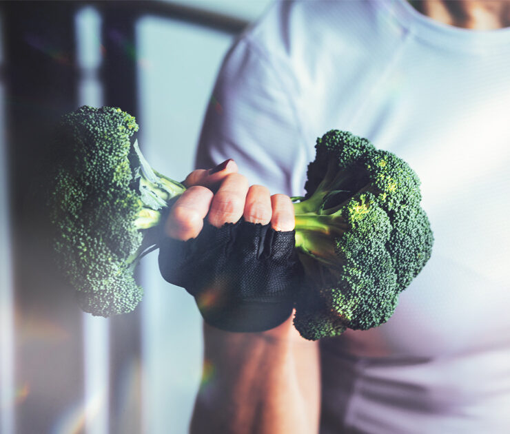 Woman in the gym lifts a broccoli in the form of a dumbbel
