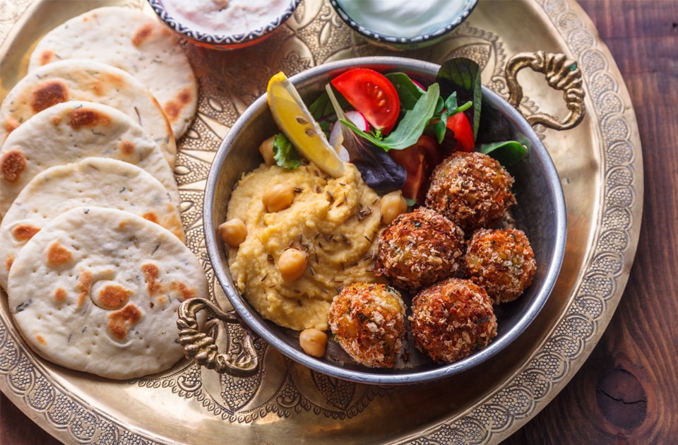 Hummus, falafel, salad and pita in a copper pan. By fazeful